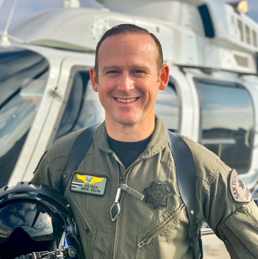 Derek Ralph, veteran owner of ID Make It, in flight gear in front of a helicopter